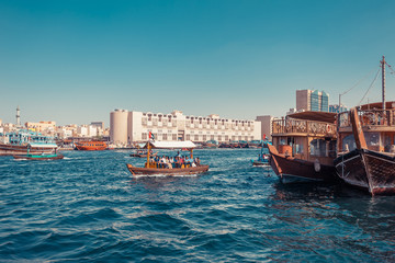 Naklejka premium Panoramic view from water taxi boats pier in Dubai, UAE. Creek gulf and Deira area. United Arab Emirates famous tourist destination. Creative color post processing.
