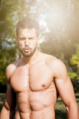 Fototapeta na wymiar Portrait of muscular young man taking a break after workout outdoors.