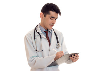 handsome young man doctor in uniform with stethoscop on his neck make notes isolated on white background