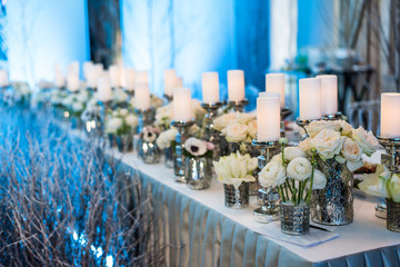 Wedding decor. Candles in candelabrum and roses. Blue background