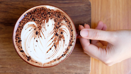 hands holding cup of coffee in coffee shop