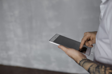 Internet technology concept. Close up shot of tablet in tattooed hands. Man use mobile for chat friends or search information. Blank area for text or product.