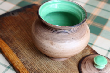 Open ceramic handmade pottery jug on wooden board