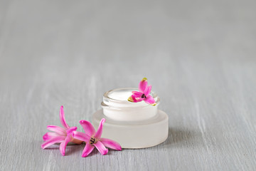 Cream in a glass jar, pink hyacinth, wooden background