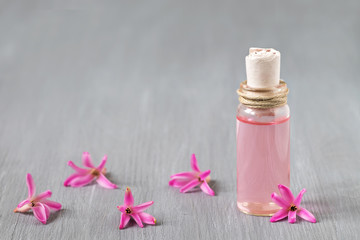 Essential oil glass bottle, pink hyacinth, wooden background