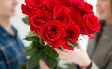 Cropped shot of unrecognizable boy gives bouquet of roses to girl in 8 march