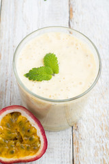 Smoothies passion fruit, milk in a glass on a white wooden background top view.