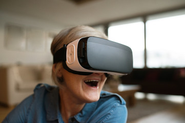 Senior woman wearing virtual reality goggles at home