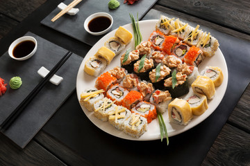 Set of sushi maki and rolls on black rustic wood