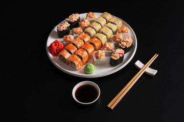 Set of salmon sushi and rolls on black background, top view