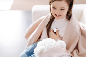 Obraz na płótnie Canvas Positive smiling girl playign with her fluffy toy