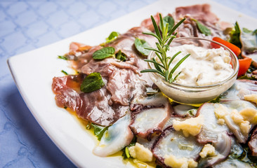 Sea food starter on white plate. Octopus and tuna carpaccio.