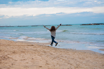Fototapeta na wymiar Happy girl jumping on the beach
