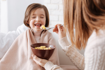 Positive little girl having breakfast with her mother