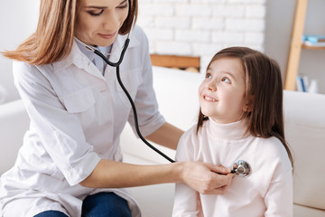 Pleasant female doctor examining little cute girl