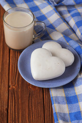 ginger biscuits in the shape of heart on a saucer and a cup of hot chocolate on a wooden table, rustic style