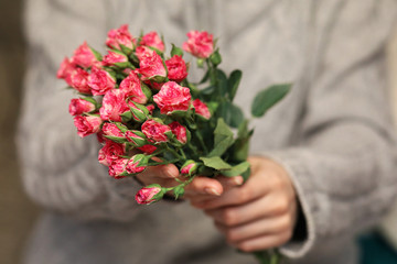bouquet of bush of roses in female hands on a background