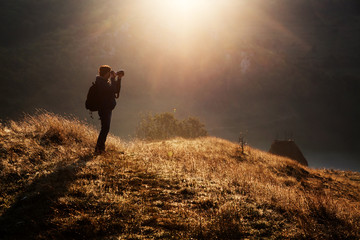 female photographer at sunrise, misty mountains