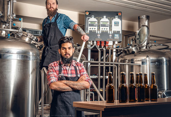 Tattooed, bearded Caucasian and Indian men in the craft beer microbrewery.
