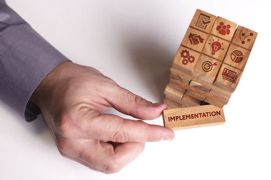 Business, Technology, Internet and network concept. Young businessman shows the word: Implementation