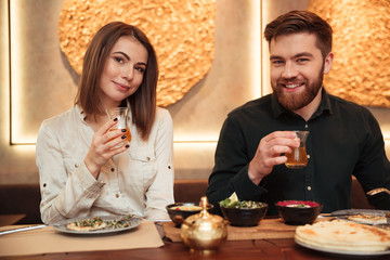 Сheerful young loving couple sitting in cafe and eating