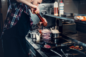 Chef cooking beef steak on a kitchen.