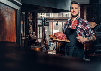 Chef with tattoos on his arms hold beef steak.