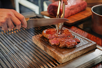 A man cooking beef steak on a grill.