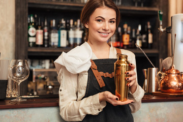 Beautiful young woman standing in cafe holding shaker
