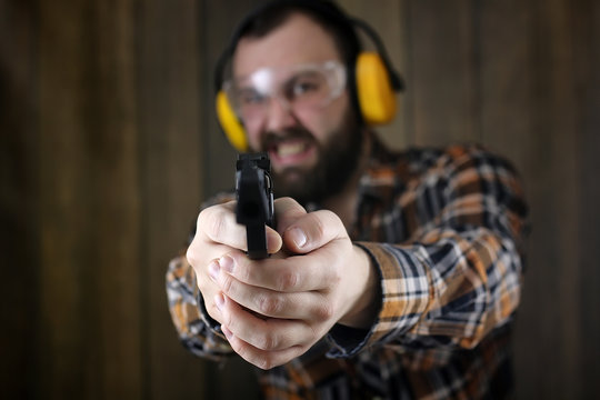 man with put on protective goggles and ear training in pistol shooting