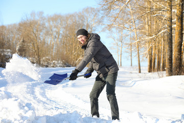 Fototapeta na wymiar man remove snow with shovel from the road in winter