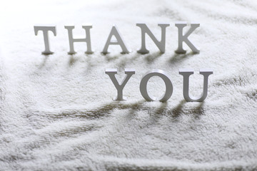 Wooden wthite letter Thank you on the crumpled carpet