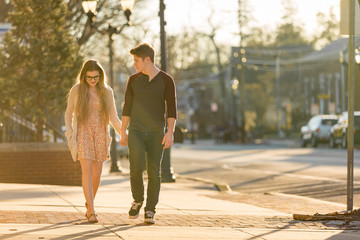 Young couple walking down the sidewalk holding hands