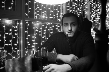 man holding hookah pipe and smoking in a night club