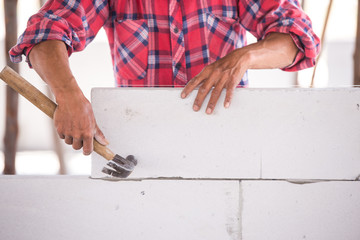 Man worker plastering and layering wall bricks.