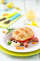 Fun food for kids - cute turtle shaped hamburger made of ground meat pattie, slices of fresh tomato and bread with Easter decoraions at the background