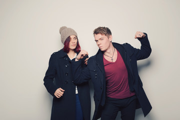 Happy young couple in winter clothes having fun in studio over white background