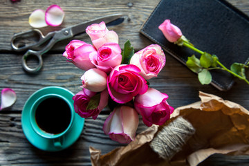 Obraz na płótnie Canvas Fresh roses with diary and cup of coffee on wooden table, top view. flowers, hot drink