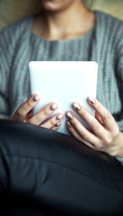 A girl holding a tablet in hands, reader with a nice manicure. Leather trousers, ugg boots. Fashion, style, learning, modern, recreation