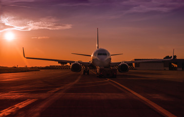Commercial passenger jet in an airport at the sunset.