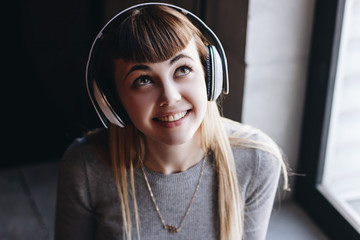 Beautiful young woman in headphones listening to music smiling