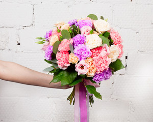 Creative bouquet of flowers at arm's length, beautiful flowers as a gift beloved.