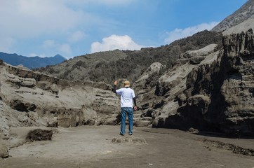 Traveler standing and wagging his finger at Bromo Mountain, Tengger Semeru national park, East Java, Indonesia.