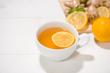 Cup of Ginger Tea with Lemon and Honey on a White Wooden Background.