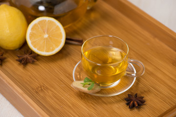 Cup of ginger tea with lemon and honey on white wooden background.