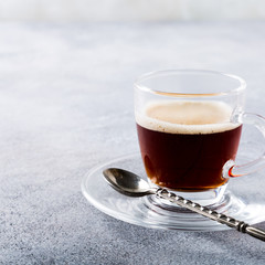 White cup of coffee on light gray background with copy space.