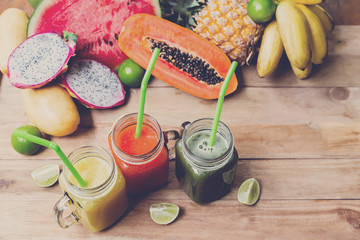 Fresh juices smoothie with tropical fruits banana, pineapple, lime melon, mango on wooden table. Top view. Healthy style raw vegan concept. Toned.