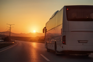 White bus driving on road towards the setting sun - 138687991