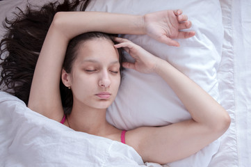 Fototapeta na wymiar Girl brunette sleeping in her bed on white pillow