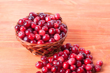 Fresh cranberries in a small basket on a wooden background